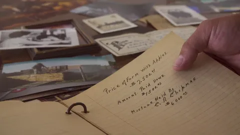 The family’s old papers and photographs, a hand holding a handwritten page about the price of the farm.