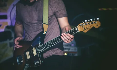 Close-up of a guitarist's hands on a Fender Jaguar with a green strap